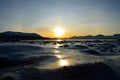 Golden sunrise over blue fjord and snowy mountain with reflection on thick ice Royalty Free Stock Photo