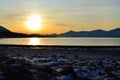 Golden sunrise over blue fjord and snowy mountain with reflection on thick ice Royalty Free Stock Photo