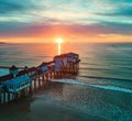 Golden sunrise over Maine ocean coast with old wood pier covered in shops