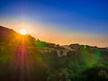 Golden sunrise over trees on the horizon of the hill with strong colorful flares and blue sky Royalty Free Stock Photo