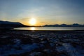 Golden sunrise over blue fjord and snowy mountain with reflection on thick ice Royalty Free Stock Photo