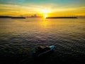 Golden sunrise and a speed boat on calm sea water with background of two islands in Talaud, north Sulawesi, Indonesia