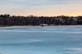 Golden sunset clouds reflecting on with ice shanty for ice fishing on frozen lake Royalty Free Stock Photo