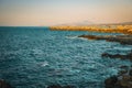 Golden Sunset Glow: Rocky Beach in Rethymno, Mountains, and Ship on the Horizon Royalty Free Stock Photo