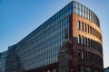 Low angle view to modern bank building with glass wall and abstract reflection in sunset golden sunlight Royalty Free Stock Photo