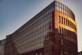 Low angle view to modern bank building with glass wall and abstract reflection in sunset golden sunlight Royalty Free Stock Photo