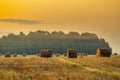 Golden sunset over farm field with hay bales. Autumn landscape Royalty Free Stock Photo