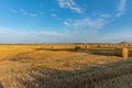 Golden sunset over farm field with hay bales and sun rays. Dry straw pressed into individual straw bales. Pile of straw Royalty Free Stock Photo