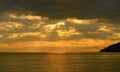 Golden sunset over sea with clouds, mountain in backlight Royalty Free Stock Photo