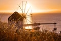 Golden sunset over sea horizon in Mykonos, Greece. Famous traditional white windmill, port, harbor, hot summer evening Royalty Free Stock Photo