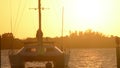 Golden sunset over water with a sailboat in foreground