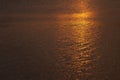 Golden sunset on sea - bright colorful orange, yellow line of last sunbeams, glare of sun on calm dark water with little ripple. Royalty Free Stock Photo