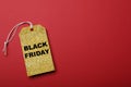 Golden tag with words Black Friday on red background, top view. Space for text Royalty Free Stock Photo