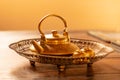 Golden tea pot in antique brass tray on wooden table, antique gold teapot,Traditional Thai style.shallow focus effect Royalty Free Stock Photo