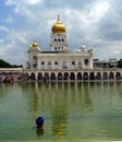 The Golden Temple and back view of a man with turban in the water with reflections, New Delhi, India Royalty Free Stock Photo