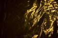 Golden texture. Background of gold film. Bright reflection in thin metal sheet. Overflow of waves