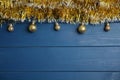 Golden tinsel and Christmas balls on blue wooden background, flat lay. Space for text Royalty Free Stock Photo