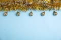 Golden tinsel and Christmas balls on light blue background, flat lay. Space for text Royalty Free Stock Photo