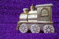 Golden toy train locomotive on a purple and lilac gradient background. New Year or Christmas card. Icicles and snow on Royalty Free Stock Photo