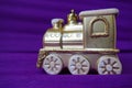 Golden toy train locomotive on a purple and lilac gradient background. New Year or Christmas card. Icicles and snow on a Royalty Free Stock Photo