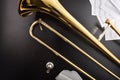 Golden trombone on a black wooden table with scores