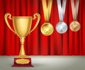 Golden trophy cup and set of medals with ribbons on red curtain Royalty Free Stock Photo