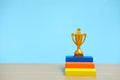 Golden trophy standing at colorful podium on wooden table