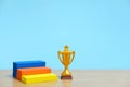 Golden trophy standing beside colorful podium on wooden table