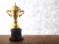 Golden trophy on wooden table over abstact white bokeh background. Winning awards with copy space.