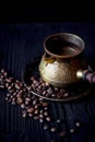 Golden Turk patterned with brewed coffee on wooden background with coffee beans