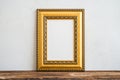 Golden vintage photo frame on old wooden table over white wall b Royalty Free Stock Photo