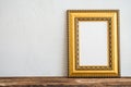 Golden vintage photo frame on old wooden table over white wall b Royalty Free Stock Photo