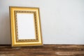 Golden vintage photo frame on old wooden table over white wall b Royalty Free Stock Photo