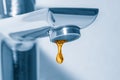 Golden water drop falling from tap close up Royalty Free Stock Photo
