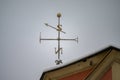 Golden weathervane with snow on top of old house roof with compass directions