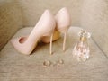 Golden wedding band and engagement ring, perfume bottle and dust pink, powdery shoes. Close up