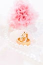Modern wedding rings with pearl necklace wih pink roses in the background Royalty Free Stock Photo