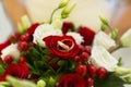 Golden wedding rings among red berries and white and red roses of wedding bouquet Royalty Free Stock Photo