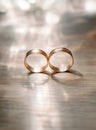 Golden wedding rings with shining bokeh on wooden surface, eternal love concept Royalty Free Stock Photo