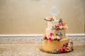 Golden wedding three-story cake. Close-up of a delicious dessert decorated with flowers, wedding cake decor. Copy space Royalty Free Stock Photo
