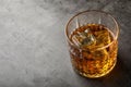 Golden whiskey in glass with ice cubes on table