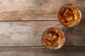 Golden whiskey in glasses with ice cubes on wooden table