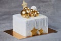 Golden white Christmas cake with chocolates golden and bronze balls. Isolated on grey.