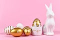 Golden and white painted easter eggs with dots and stripes, cute easter egg cup in shape of bunny and rabbit figure on pink backgr Royalty Free Stock Photo