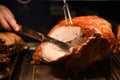 Golden whole roast turkey joint of meat being carved with a knife and the hand is visible