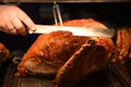 Golden whole roast turkey joint of meat being carved with a knife and the hand is visible