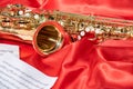 Golden musical instrument alto saxophone on red fabric with music sheets Royalty Free Stock Photo