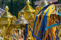 Golden winner's cups with yellow and blue ribbons prepared for awards in a row on the table on sky background Royalty Free Stock Photo