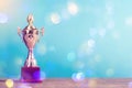 Golden winner`s trophy on sky background standing on wooden desk festive bokeh blur backgrounds