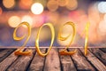 Golden 2021 on wood table top with blurred lights background new year holiday greeting card